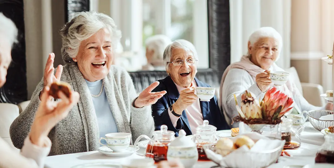 Residents celebrating together at a dining table in a Prima Living community.